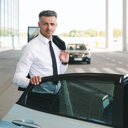 Smiling mature businessman getting in taxi outside